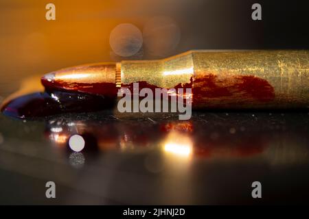 AR-15-Stil Gewehrpatrone und Blut (Fototafel). Stockfoto