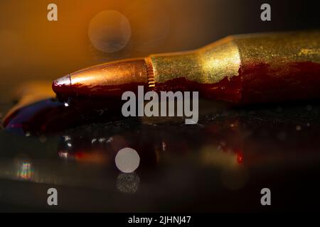 AR-15-Stil Gewehrpatrone und Blut (Fototafel). Stockfoto