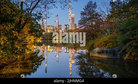 Herbstlaub in Dawn im Central Park mit See und Skyline Stockfoto