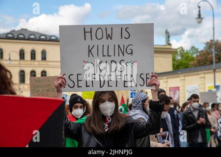 Demosntrantin hält ein Schild mit der Aufschrift: „ wie können Kinder töten Selbstbeteiligung sein? ' Ca. 600 Menschen sammeln sich am 20.5.2021 in München, um ihre Solidarität mit den Menschen in Gaza, Ost Jerusalem, den besetzten Gebieten und dem Westjordanland zu zeigen. - der Protestierende hält ein Schild mit der Aufschrift: " wie ist das Töten von Kindern Selbstverteidigung? Rund 600 Menschen versammelten sich am 20. Mai 2021 in München, Deutschland, um ihre Unterstützung für die Menschen in Gaza, Ostjerusalem, den besetzten Gebieten und der Westbank zu zeigen. (Foto: Alexander Pohl/Sipa USA) Quelle: SIPA USA/Alamy Live News Stockfoto