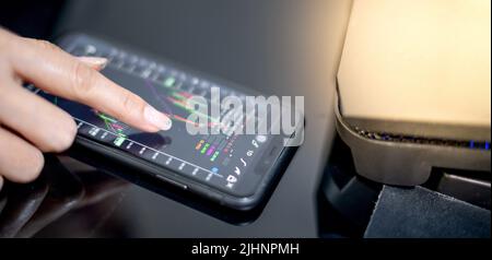 Die Analystin des Anlegermaklers hält ein Smartphone in der Hand und analysiert die Aktienmarkt-Trading-Charts, indiziert Daten zur Preisprüfung mithilfe von Mobiltelefonen. Stockfoto