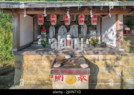 nagasaki, kyushu - dezember 14 2021: Statuen der buddhistischen Jizô, Kannon, Benzaiten oder Fudô-Myô, geschmückt mit Papierlaternen, Blumen und shide-Papier Stockfoto