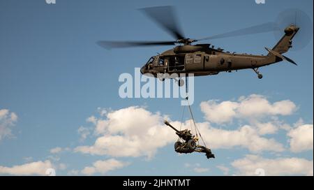 UB-60 Hubschrauber-Piloten von Blackhawk, die dem Bataillon 3. zugewiesen wurden, 227. Aviation Regiment tragen einen dem Alpha Battery zugeordneten Howitzer M119A3, 1. Bataillon, 320. Field Artillery Regiment, 2. Brigade Combat Team „STRIKE“, 101. Airborne Division (Air Assault) während der Aufzugbohrer im Rahmen der Sling Load Operationen am 18. Juli 2022, In Mihail Kogalniceanu, Rumänien. Die schreienden Adler von heute sind bereit, unsere Verbündeten zu unterstützen, um die langfristige Stabilität in Europa zu bewahren, für die unsere Vorgänger gekämpft und gestorben sind. (USA Foto der Armee von Staff Sgt. Malcolm Cohens-Ashley, 2. Brigade Comba Stockfoto