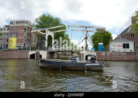 Kleines Boot auf der Amstel vor einer Zugbrücke in Amsterdam Stockfoto