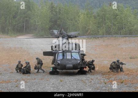 Mannschaftsoffiziere der Polizeibehörde von Anchorage, Special Weapons and Tactics (SWAT), verlassen eine Nationalgarde der Alaska Army UH-60L Black Hawk, die von einer Luftbesatzung betrieben wird, die dem Bataillon 1., 207. Aviation Truppenkommando auf der Joint Base Elmendorf-Richardson, Alaska, zugewiesen wurde, 13. Juli 2022. Die umfangreichen und strengen Trainingsbereiche von JBER boten den SWAT-Teams der lokalen Strafverfolgungsbehörden einen idealen Rahmen, da sie ihre Fähigkeiten im ländlichen Betrieb, die Aufgabenplanung, die Aufklärung, die Sicherheitsverfahren für Hubschrauber, die Landnavigation, Teambewegung und Patrouille. (USA Luftwaffe Foto von Alejandro Peña) Stockfoto