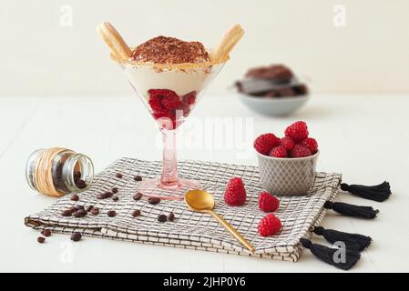 Einfach und schnell hausgemachte Himbeer-Tiramisu mit Schokolade und Kaffee, süßes Käsekuchen-Dessert mit Zutaten auf weißem Holztisch platziert Stockfoto