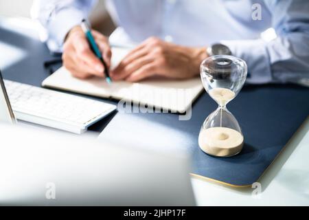 Nahaufnahme der Sanduhr Vor dem Unternehmer Hand Berechnung Rechnung Stockfoto