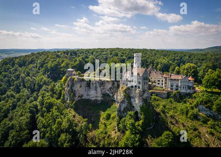 Luftaufnahme von schloss lichtenstein auf bewaldeten Felsklippen in den Schwäbischen Alpen im Sommer. Saisonales Panorama des romantischen Märchenpalastes im gotischen Revival-Stil über dem Himmel. Berühmtes europäisches Wahrzeichen Stockfoto