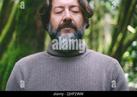 Nahaufnahme Porträt von Senior Map mit geschlossenen Augen im inneren Gleichgewicht ruhige Meditation allein mit grünen Wald Natur im Hintergrund. Positiver Lebensstil f Stockfoto