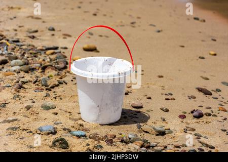 Nahaufnahme eines weißen Plastikspielzeug-Eimers für Kinder am Strand. Stockfoto