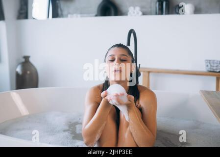 Die junge Frau genießt den Schaum beim Baden Stockfoto