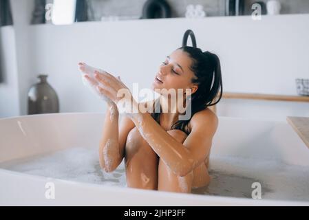 Die junge Frau genießt den Schaum beim Baden Stockfoto