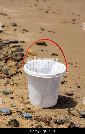 Nahaufnahme eines weißen Plastikspielzeug-Eimers für Kinder am Strand. Stockfoto