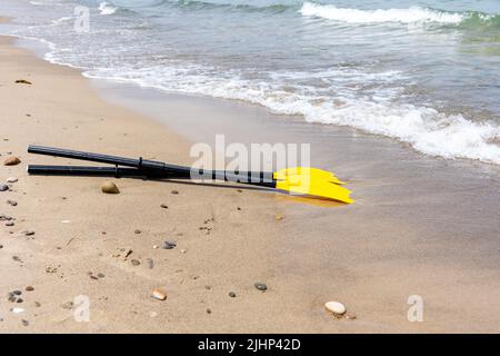 Gelbes Kajakpaddeln am Kiesstrand. Kajak-Sportausrüstung. Stockfoto