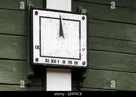 Quadratische vintage Sonnenuhr auf einer grünen Holzwand platziert Stockfoto