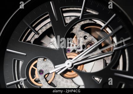 Nahaufnahme des schwarzen Deals und der Hände einer mechanischen Schweizer Skelett-Armbanduhr Stockfoto