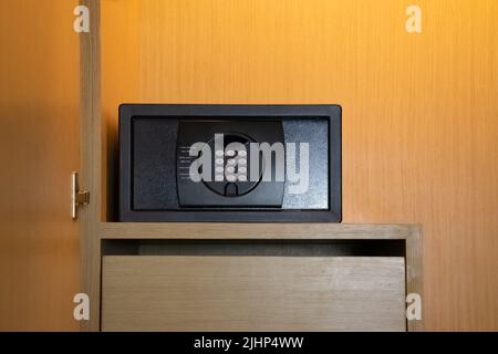 Ein grauer Safe im Kleiderschrank. Es ist ein kleiner Safe, in dem Wertsachen aufbewahrt werden können, während Sie unterwegs sind. Stockfoto