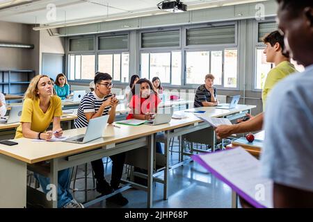 Junge Gruppe von verschiedenen Gymnasiasten, die eine Präsentation im Klassenzimmer halten Stockfoto