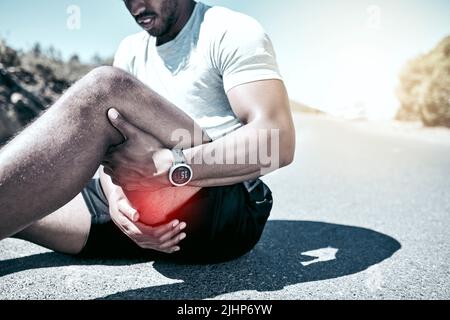 Closeup FIT gemischter Rennmensch, der sein Bein vor Schmerzen hält, während er im Freien trainiert. Nicht erkennbarer männlicher Athlet, der an einer Muskelverletzung am Oberschenkel leidet Stockfoto