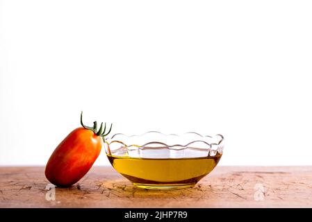 Olivenöl. Spanien Olivenöl in Glas transparente Schüssel mit Tomaten. Nahaufnahme, isoliert auf weißem Hintergrund. Stockfoto