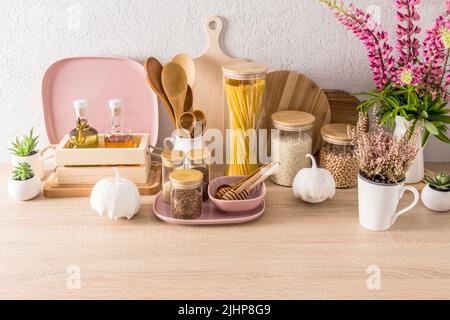 Verschiedene Glasgefäße mit Holzdeckel, Glasflaschen mit Öl, Dekorelemente auf einer modernen Küchenarbeitsplatte. Innenraum des Hauses Stockfoto