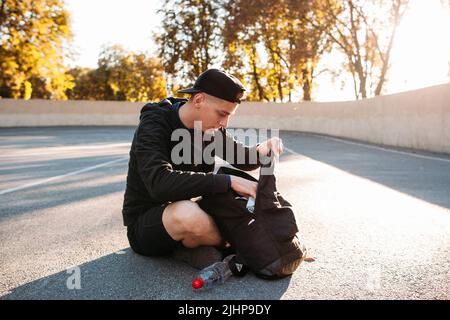 Junger Mann auf der Suche nach etwas in seiner Tasche Stockfoto