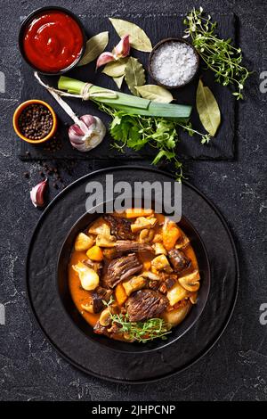 Rindfleisch Bourguignon, Rindfleisch Burgund, Eintopf mit Rindfleisch, Speck, Karotten, Zwiebeln und Pilze langsam in reicher Rotweinsauce in schwarzer Schüssel mit Zutat gekocht Stockfoto