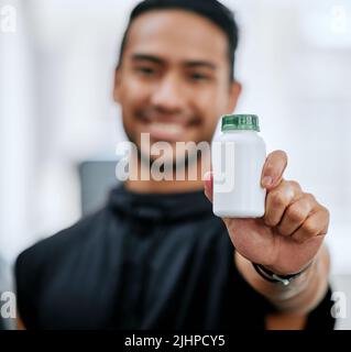 Blur lächelnden Trainer allein im Fitnessstudio, während halten und zeigen Flasche Steroid-Pillen. Asiatischer Trainer mit hormonverstärkenden Medikamenten für das Training in der Übung Stockfoto