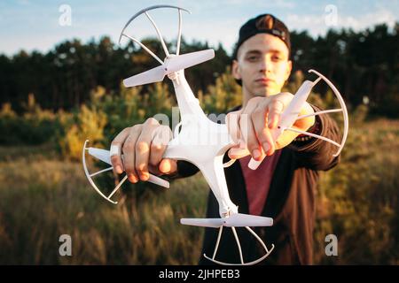 Junger Mann, der Drohne mit beiden Händen hält Stockfoto
