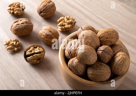 Ganze geschälte Walnüsse und gerissene Walnüsse auf Holzgrund Stockfoto