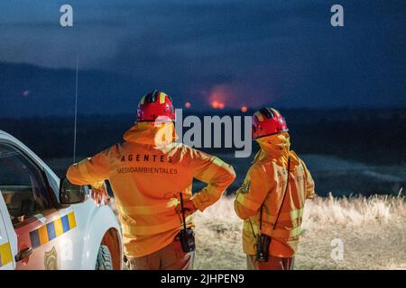 Madrid, Spanien. 19.. Juli 2022. Zwei Feuerwehrleute beobachten den Rauch und das Feuer von Valdepeñas de la Sierra. Das Feuer der Valdepeñas de la Sierra in Guadalajara verwüstet 2.300 Hektar und hinterlässt Dutzende von Familien obdachlos. Die Brände ereigneten sich im Zusammenhang mit der Sommersaison und den hohen Lufttemperaturen und starken Winden, doch die Behörden schließen nicht aus, dass das Feuer hätte provoziert werden können. Kredit: SOPA Images Limited/Alamy Live Nachrichten Stockfoto