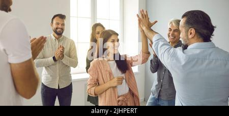 Glücklicher Mann und Frau, die sich während des Workshops mit dem Business Coach gegenseitig hohe fünf gaben Stockfoto