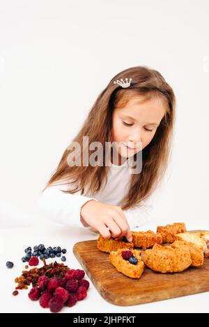 Mädchen, das süße Kuchen mit Beeren zubereitet Stockfoto