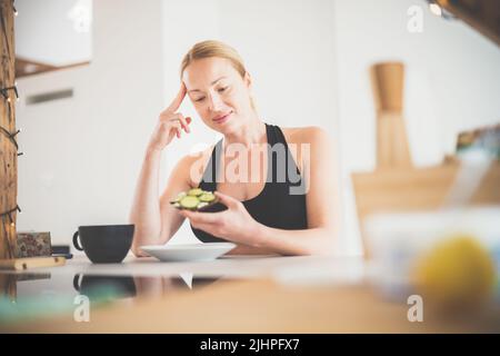 Schöne sportliche fit junge Schwangeren mit einem gesunden Snack in der Küche zu Hause. Gesundes Lifestyle-Konzept. Stockfoto