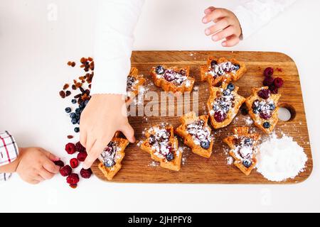 Mädchen setzen süße Kuchen an Bord, kleine Junge Hand Stockfoto