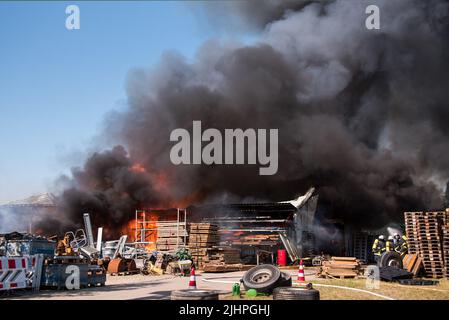 Hamburg, Deutschland. 20.. Juli 2022. Feuerwehrleute löschen ein brennendes Lagerhaus im Landkreis Altengamme. Die Halle, in der Landmaschinen und Holz gelagert wurden, war am Morgen in vollem Feuer. Quelle: Daniel Bockwoldt/dpa/Alamy Live News Stockfoto