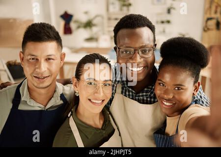 Eine Gruppe verschiedener Designer, die ein Selfie machen. Glückliche Kollegen, die ein Foto machen. Junge Modedesigner, die im Studio ein Selfie machen. Gruppe von Stockfoto