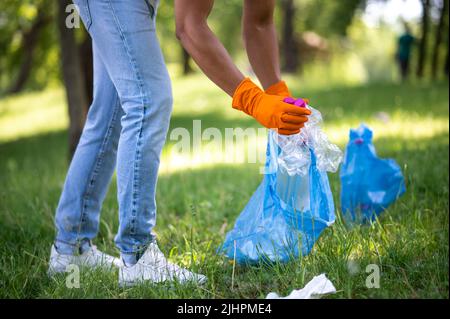 Die untere Hälfte des Mannes, der Müll im Park aufsammelt Stockfoto