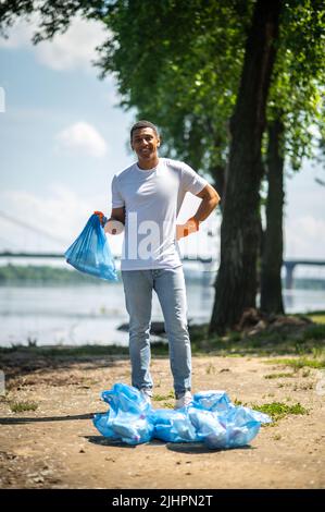 Typ mit Müllsack, der auf die Kamera schaut Stockfoto