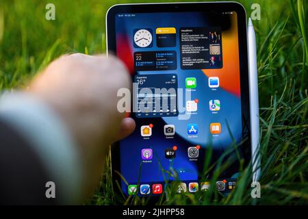 Paris, Frankreich - 21. Oktober 2021: POV männliche Hand hält im grünen Gras neue Apple Computers iPad Mini 6. Generation Tablet mit Bleistift auf dem Magneten und alle Home-Bildschirm-Menü Stockfoto