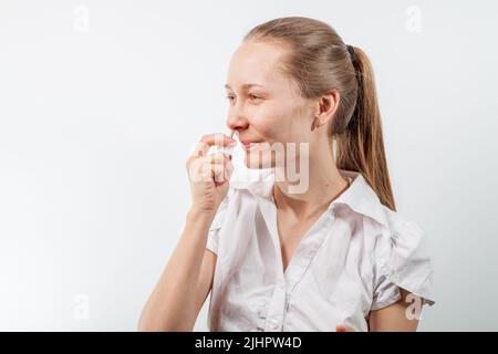 Das Mädchen tropft Nasentropfen aus einer laufenden Nase mit Influenza Stockfoto