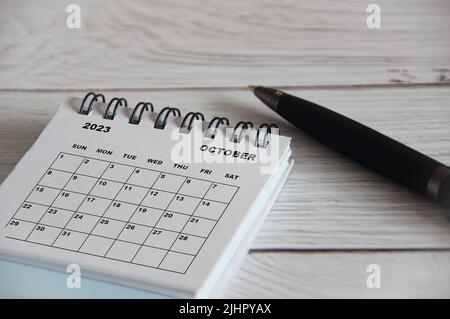 Oktober 2023 weißer Tischkalender mit schwarzem Stift auf Holztisch. Kalenderkonzept Stockfoto