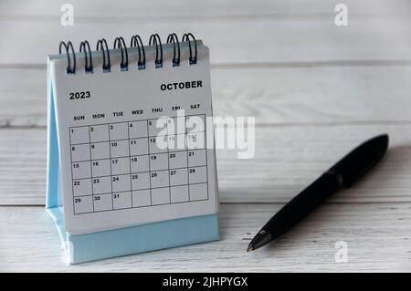 Oktober 2023 weißer Tischkalender mit schwarzem Stift auf Holztisch. Kalenderkonzept Stockfoto