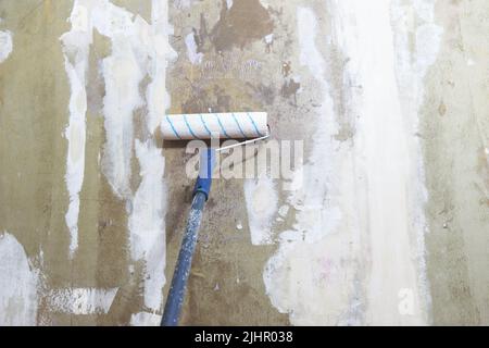 Die Gipskartonwand mit einer Walze mit einer Grundierung abdecken Stockfoto