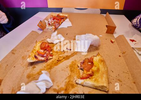Halbgefressene Pizzascheiben nach dem Mittagessen auf dem Tisch Stockfoto