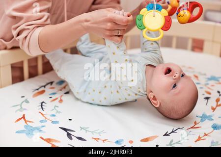 Babymassage. Mutter macht Gymnastik mit neugeborenem Kind Stockfoto