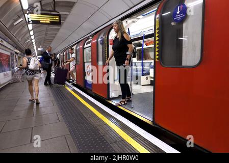 London, England, Großbritannien. London Underground - Frau mit Ellenbogenkrücke beim Aussteigen aus einem U-Bahn-Zug Stockfoto