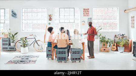Eine Gruppe von verschiedenen Geschäftsleuten, die sich in einem modernen Büro auf der Arbeit treffen. Junger glücklicher afroamerikanischer Geschäftsmann, der eine Idee vorführt Stockfoto