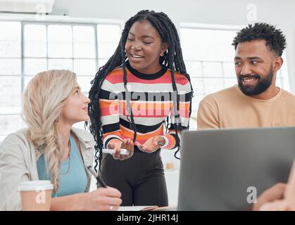 Eine Gruppe von verschiedenen Geschäftsleuten, die sich in einem modernen Büro auf der Arbeit treffen. Junge afroamerikanische Geschäftsfrau, die mit ihren Kollegen spricht, während sie Stockfoto