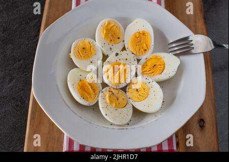 Halbgekochte Eier mit gemahlenem Pfeffer und Salz auf einem Teller Stockfoto